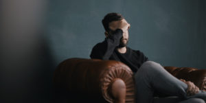 Man on a leather lounge holding his head